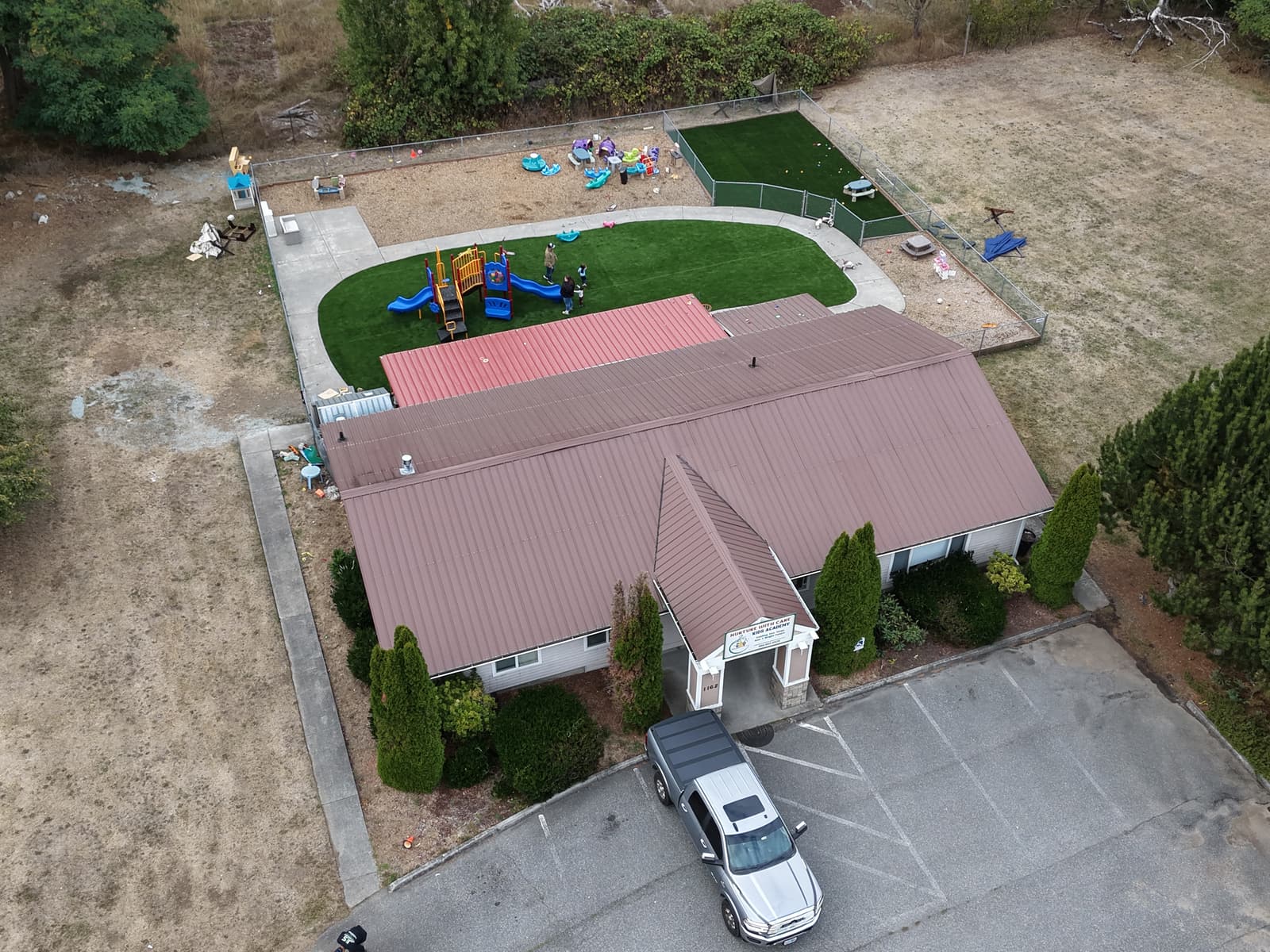 Aerial view of the Fort Nugent property showing the building, entrance sign, parking lot, playground and both fenced play yards