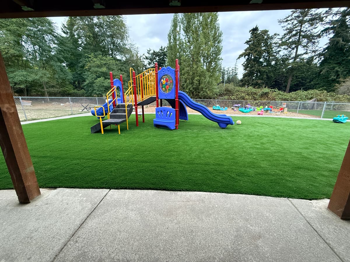 View out across the turf playground from under the covered patio at Fort Nugent, framed between the shelter posts