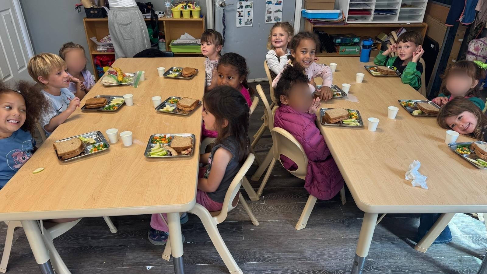 Children eating lunch at Nurture with Care Kids Academy, sandwiches and vegetables on stainless trays