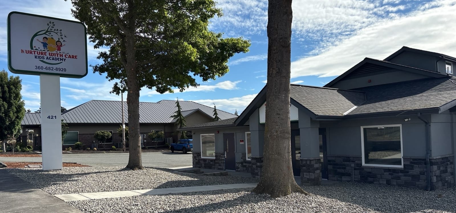 Our new Midway Blvd location in Oak Harbor, with the NURTURE WITH CARE KIDS ACADEMY sign and the gray craftsman building at 421 NE Midway Blvd