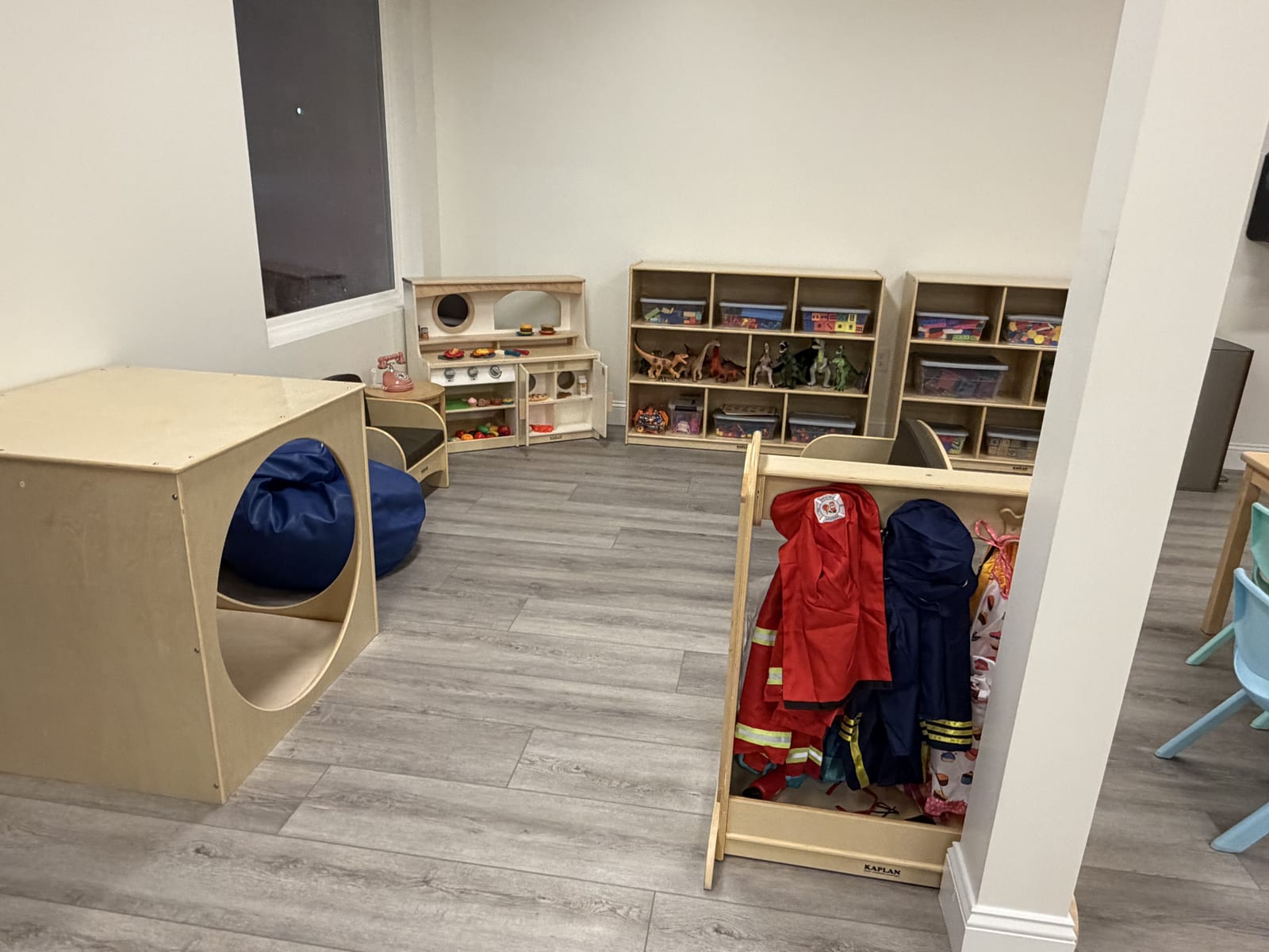 Dress-up rack with costumes next to a cozy cube nook and toy shelving