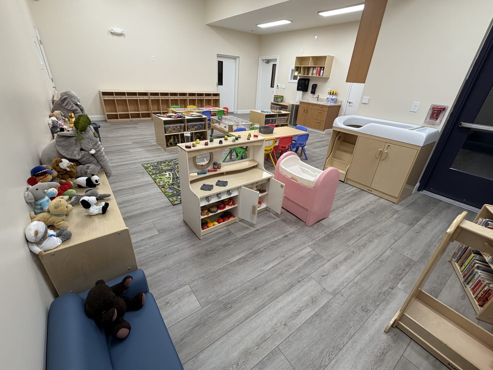 Young toddler classroom with cubbies, a reading bench, a small slide, and a changing station
